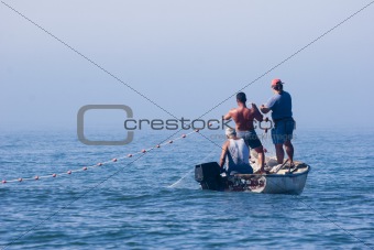 fishermen in their boat pulling nets