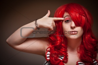 Portrait of an Attractive Red Haired Woman with Hand in the Shape of a Gun to Her Head on a Grey Background.