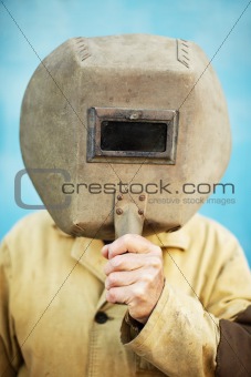 Old welder's helmet in hands of welder