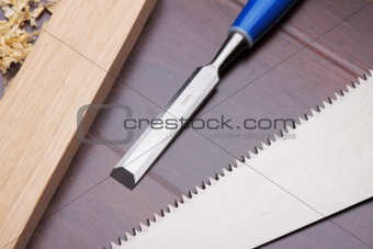 Wooden brick, chisel and handsaw on the floor