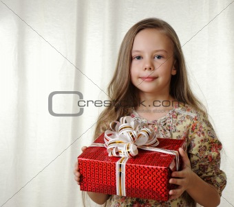Little girl holds a red box with a gift