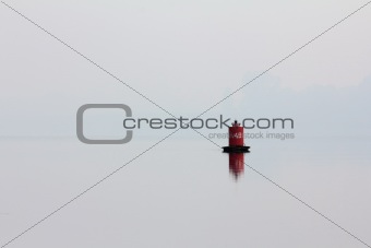 red buoy on river in mist