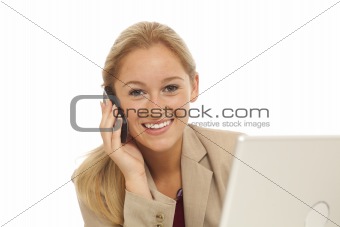Portrait of young business girl using cell phone at desk with laptop