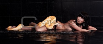 Beautiful woman lying with Python in water