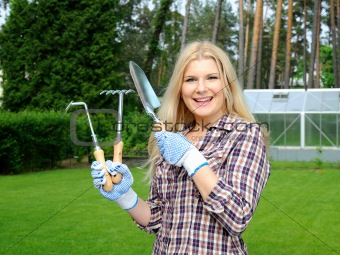 Pretty gardener woman with gardening tools outdoors. greenhouse 