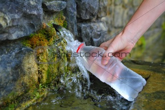 source of spring water bottle filling holding hand