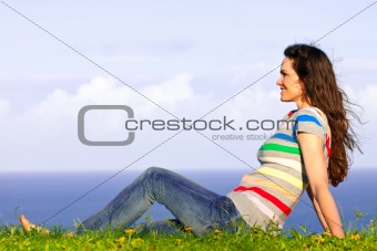 Beautiful young happy woman relaxing in the grass by the ocean