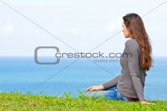 Sad and upset young beautiful woman sitting by the ocean
