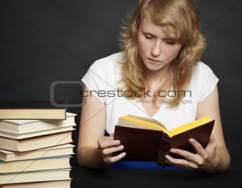 Young woman reads book against dark background