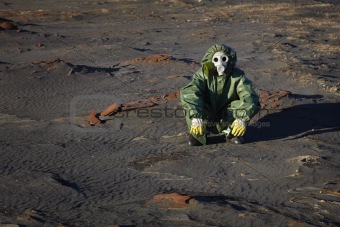 Man in protective clothing sitting in desert