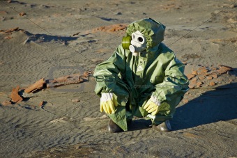 Scientist in protective suit and gas mask sitting on slag