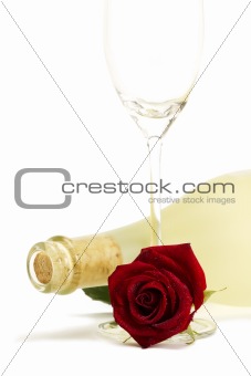 wet red rose with a dull prosecco bottle and a empty champagne glass