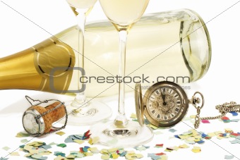 two glasses with champagne, old pocket watch, cork and confetti in front of a champagne bottle