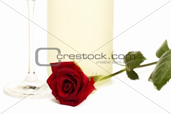 wet red rose in front of a prosecco bottle and a champagne glass