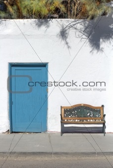 Teal Door and Bench against a Rustic Whitewashed Wall