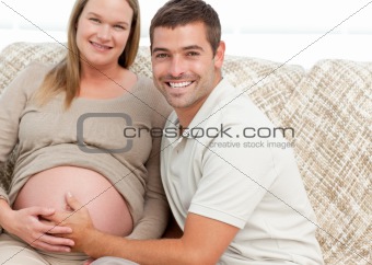 Happy future mom and dad relaxing in their living room