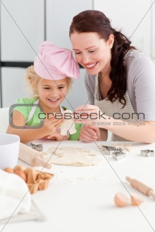 Cheerful mother and daughter making cookies in form of a man 