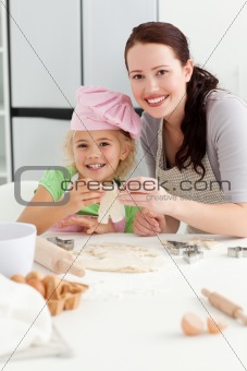 Happy girl with her mother baking little cakes