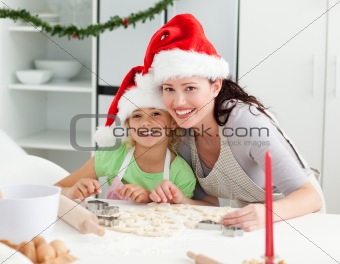 Portrait of a cute girl with her mother baking Christmas cookies