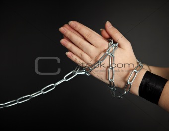 Women's hands shackled a metal chain