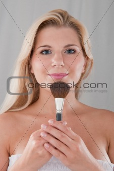 beautiful girl applying powder make-up with brush