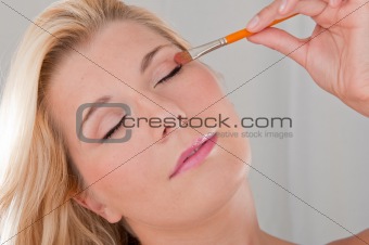 beautiful girl applying eye make-up with brush