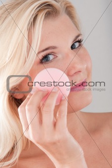 beautiful girl cleansing her face with sponge