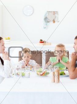 Parents and their children praying during their lunch