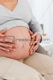 Close p of future parents feeling their baby sitting on the bed
