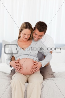 Cute future parents looking at the belly of the woman sitting