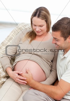 Beautiful future parents feeling their unborn child sitting