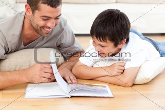 Cute boy reading a book with his father on the floor