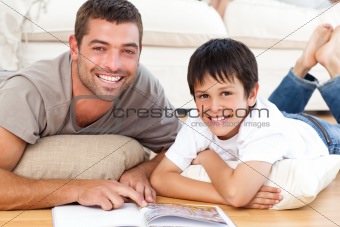 Portrait of a father and son reading a book together on the floor