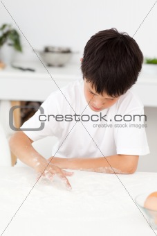 Cute boy playing with floor while cooking alone