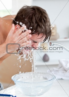 Attractive caucasian man spraying water on his face after shaving