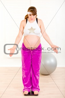 Dissatisfied with her weight pregnant woman standing on weight scale
