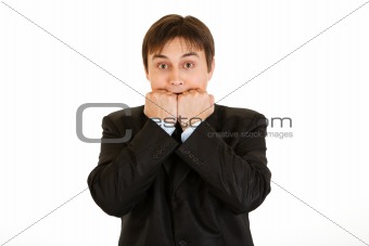 Scared young businessman holding hands near  mouth
