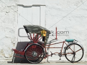 Trishaw parked at a white wall