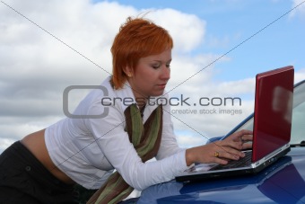 young woman with notebook on cowl of car