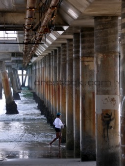Woman running on shore under pillared walkway