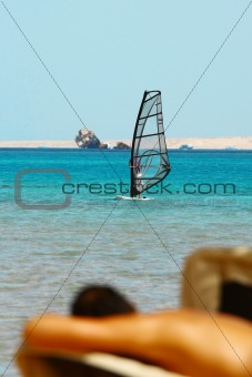 Man tans on windsurfing background