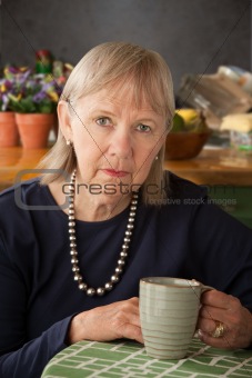 Depressed senior woman with mug
