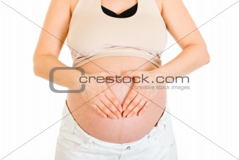 Pregnant woman making heart with her hands on belly.  Close-up.

