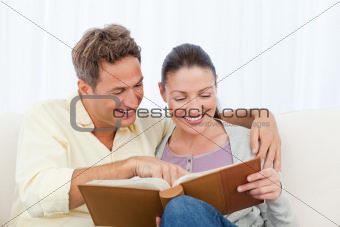 Couple smiling while looking at pictures on a photo album
