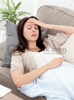 Sick woman lying on the sofa and touching her forehead 