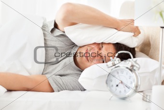 Stressed man looking at his alarm clock ringing 