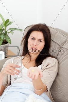 Sick woman showing a pill to the camera