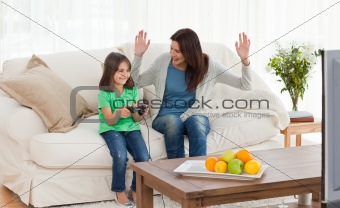 Cheerful mom looking at her daughter playing video games