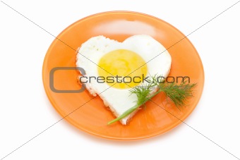 Fried egg in form heart on plate with dill