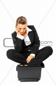Sitting on  floor bored modern business woman looking in laptop
